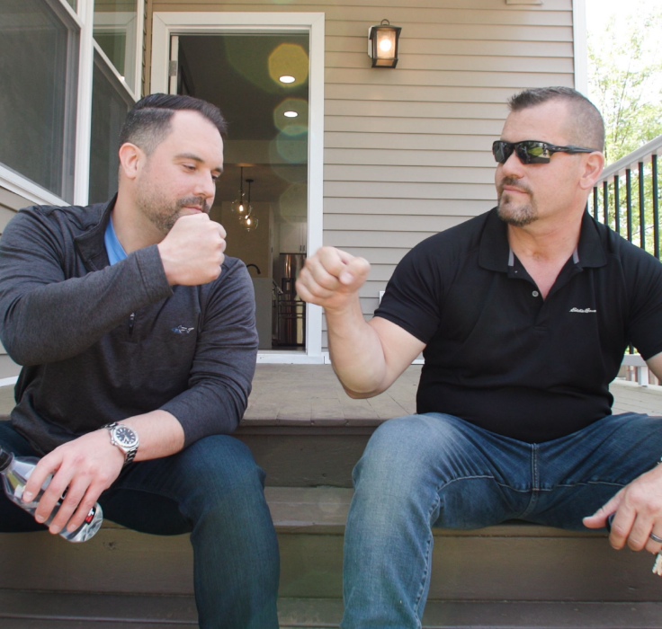 Two investors talking on the front steps of a renovated home